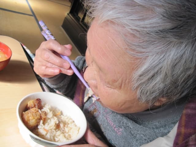 歯の片側ばかり使用して食事する高齢女性