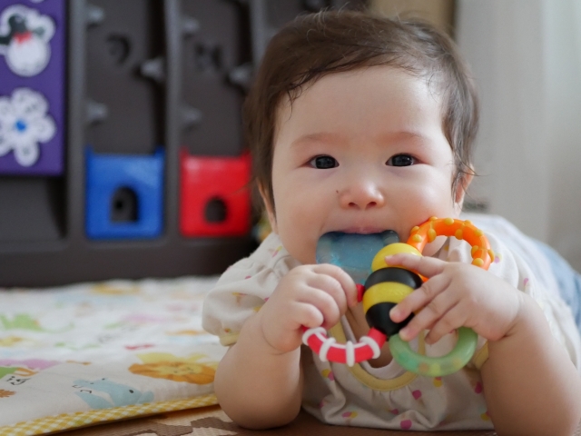 歯がむずむずしておもちゃを口に入れる赤ちゃん